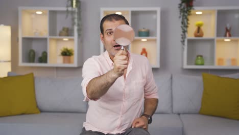 Man-looking-at-camera-with-magnifying-glass.
